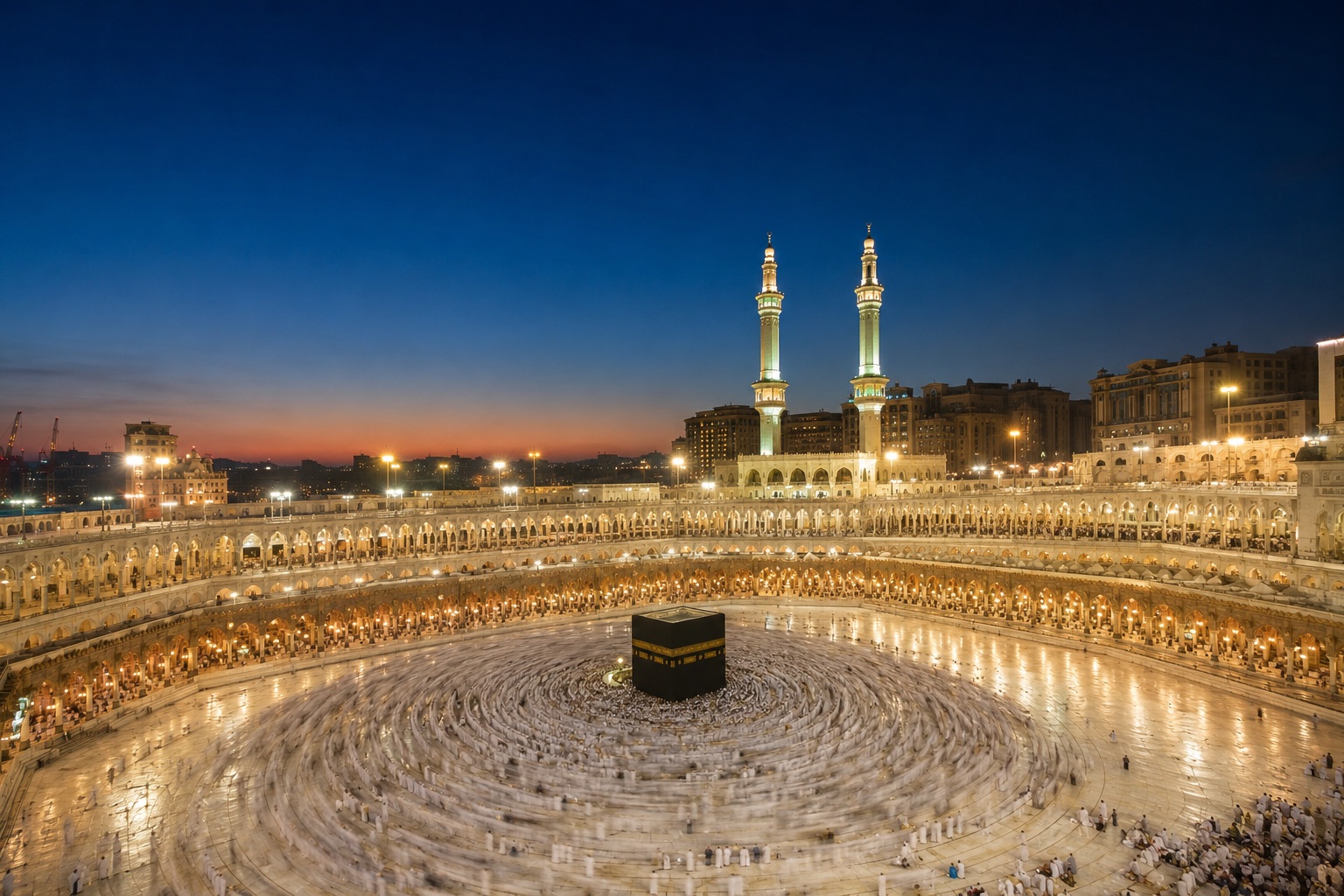 The illuminated courtyard of Masjid al-Haram in Makkah surrounding the Kaaba at dusk.