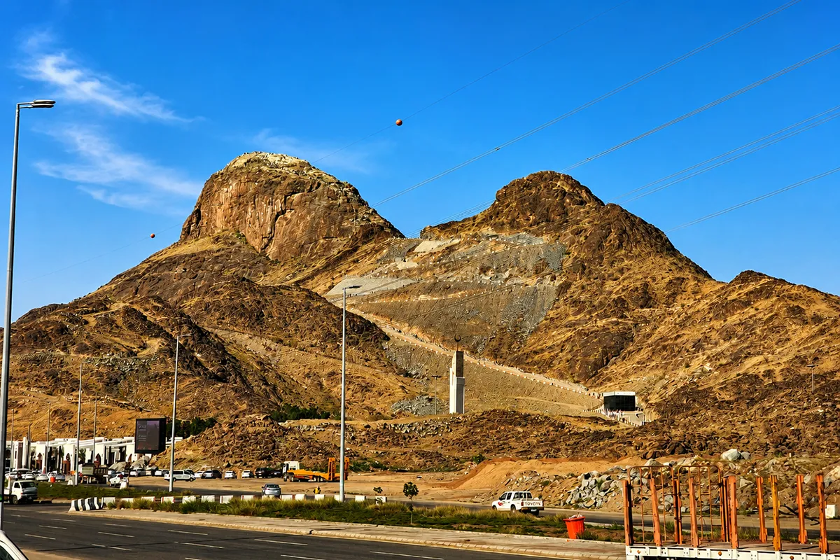 Jabal al-Noor rising above the northern edge of Makkah in late afternoon light, its distinctive humped summit and bare rocky slopes above the low buildings at its base.