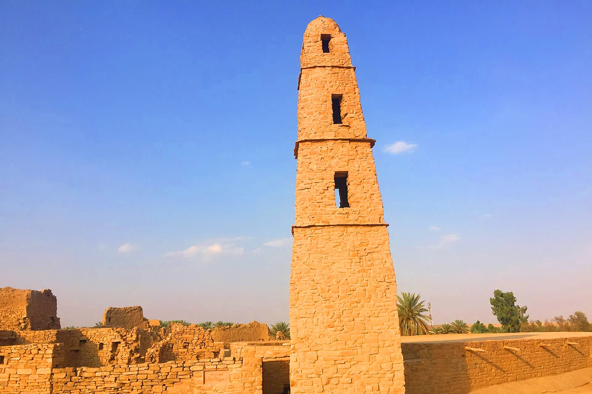 The five-tiered tapering stone minaret of the Umar mosque at Dumat al-Jandal, ending in a small pyramid, above the flat roof of the prayer hall.