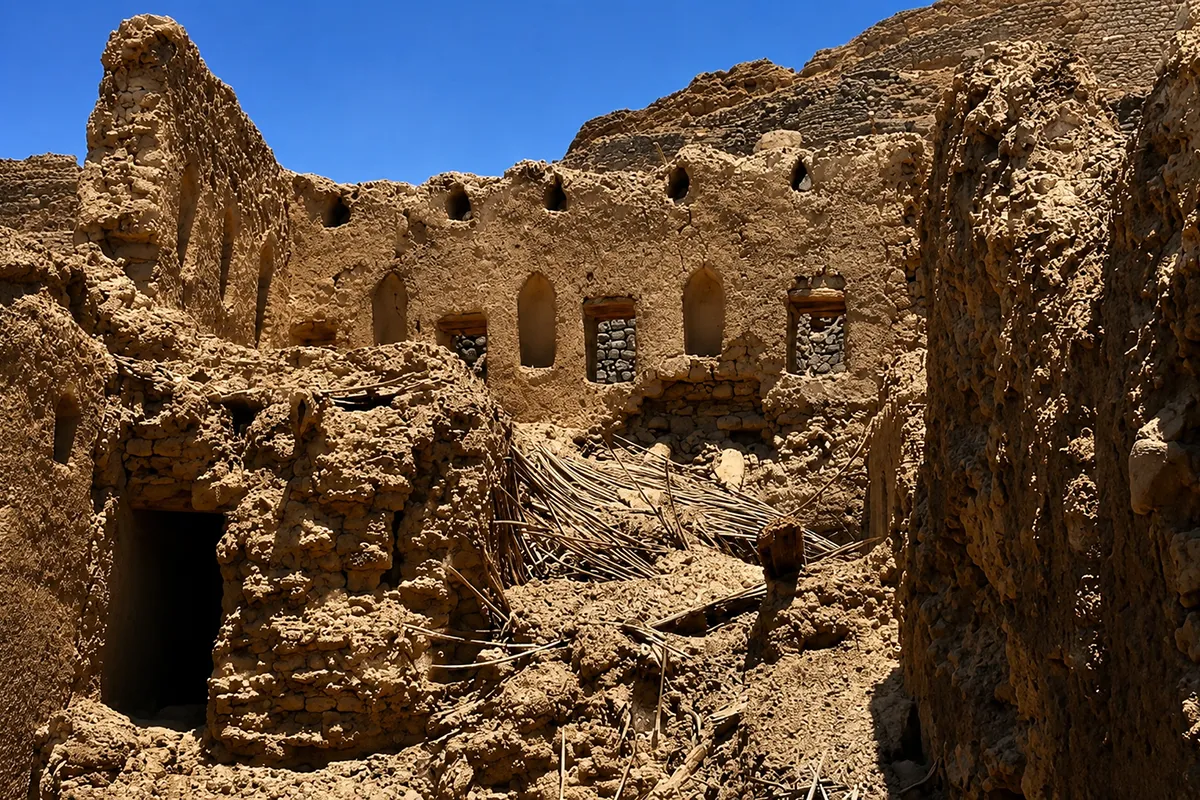 Ruined stone walls of a hilltop fortress at Khaybar standing on high rocky ground above dry country, unrestored, in late afternoon light.