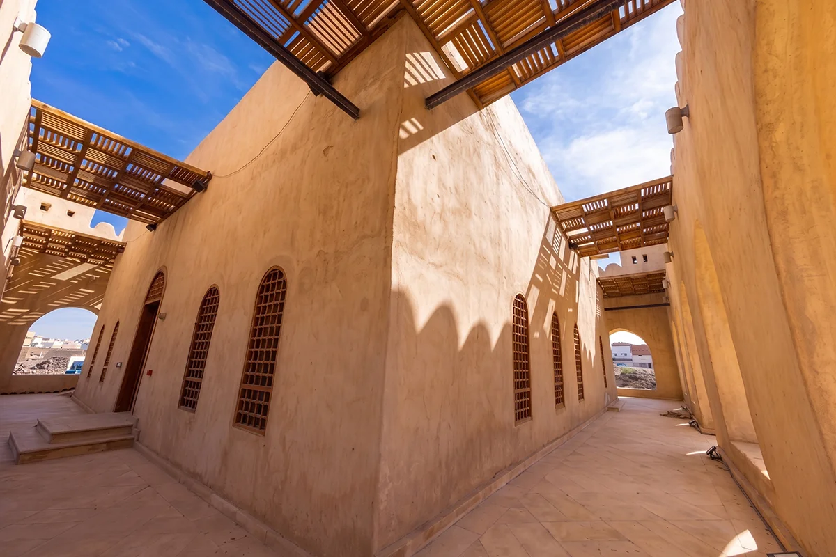 Low stone and basalt foundation walls of an early Islamic courtyard house on the bank of Wadi al-Aqiq west of Madinah, seen in raking morning light.