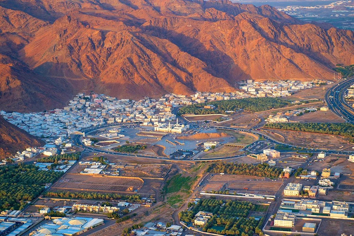 The long red-brown ridge of Mount Uhud rising above the flat open plain north of Madinah in early morning light, with the low archers' hill in the middle distance.