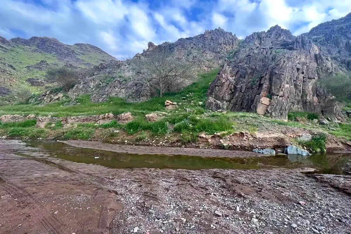 A bare rocky mountain rising above dry open valley country on the old inland road north of Makkah, seen in low morning light with no buildings or signs nearby.