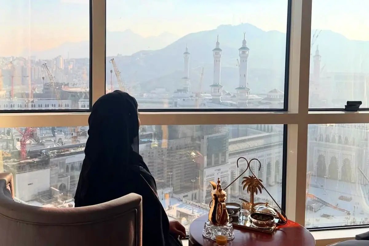 Steep granite slopes on the northern side of Makkah near Jarwal, apartment blocks built up the hillside, a cut rock face at street level and the minarets of the Grand Mosque visible beyond.