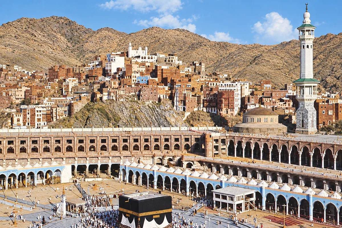 The cut rock face and terraced construction on the western side of the Grand Mosque in Makkah, where the ridge of Jabal Qu'ayqi'an once stood, cranes and hotel towers rising above the excavated slope.
