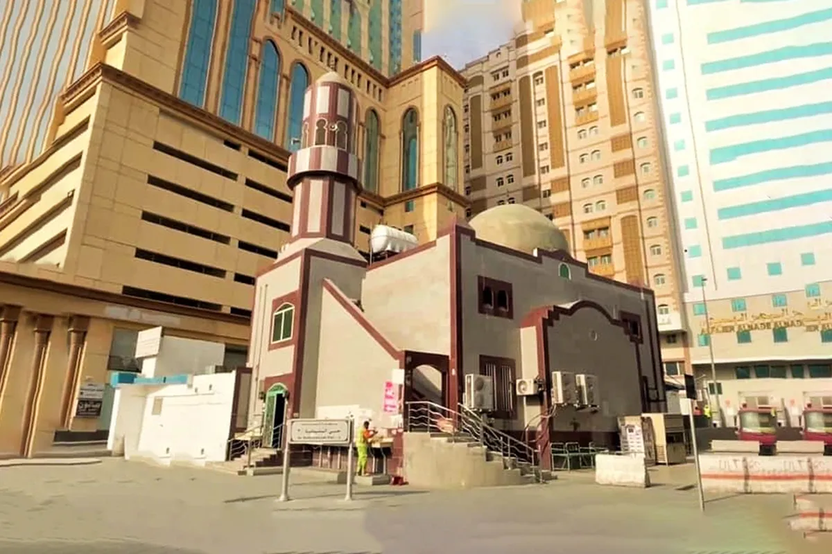 The wide new northern courtyards of the Grand Mosque in Makkah at al-Hujun, pale marble and construction cranes where the small Masjid al-Rayah once stood, pilgrims crossing as blurred anonymous shapes.